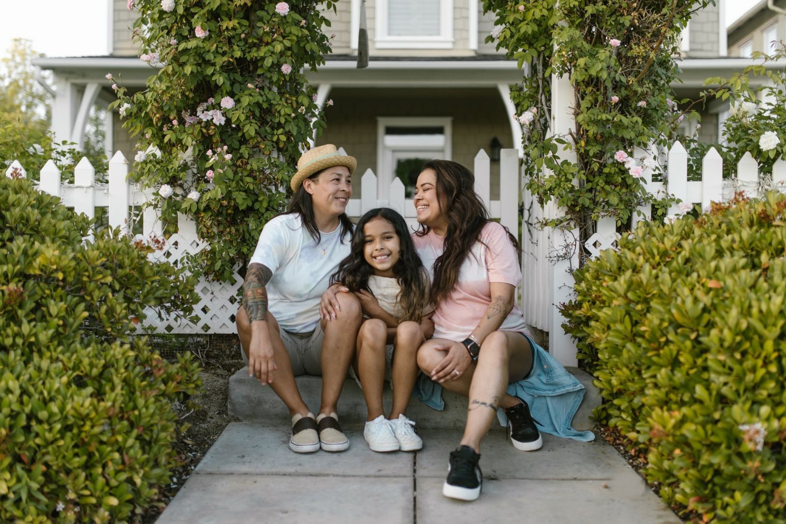A family sitting close together on a porch bench in late-afternoon daylight, relaxed and unhurried, looking out past
